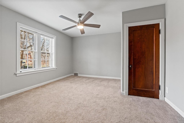 carpeted spare room with a ceiling fan, visible vents, and baseboards