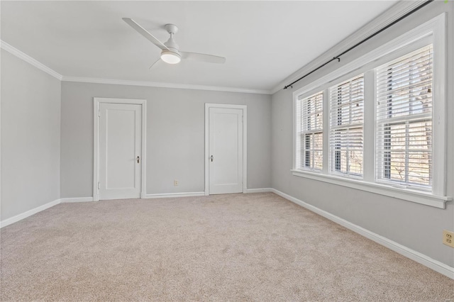 unfurnished bedroom featuring ceiling fan, light carpet, multiple closets, baseboards, and ornamental molding