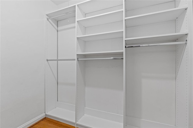 walk in closet with wood finished floors