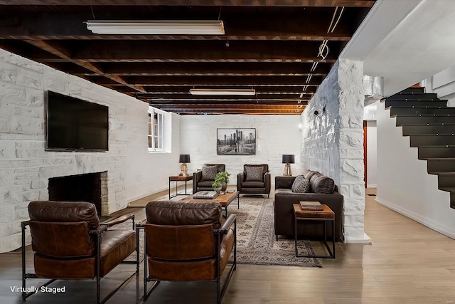 living area featuring a fireplace, stairway, baseboards, and wood finished floors