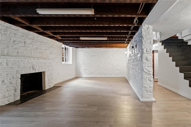 below grade area featuring stairs, a fireplace, and wood finished floors