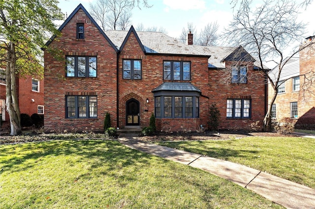 view of front of house with a front yard, brick siding, a chimney, and a high end roof