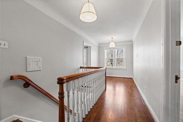 hallway with baseboards, an upstairs landing, and wood finished floors