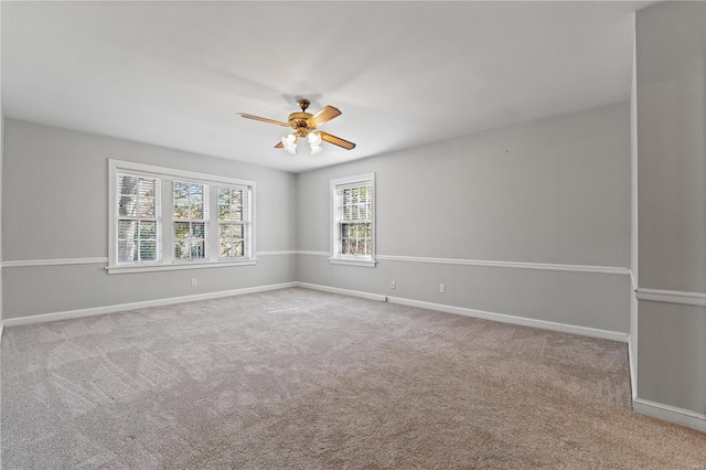 carpeted spare room featuring ceiling fan and baseboards