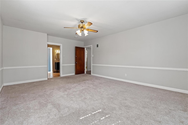 carpeted spare room with visible vents, ceiling fan, and baseboards