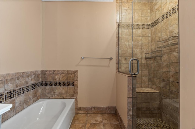 bathroom featuring a stall shower, a bath, and baseboards