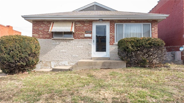 bungalow with a front yard and brick siding