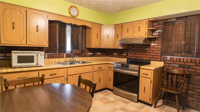 kitchen featuring white microwave, under cabinet range hood, a sink, light countertops, and stainless steel range with electric stovetop