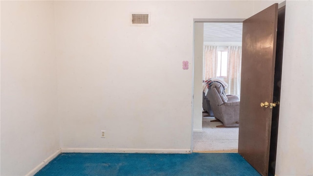 unfurnished room with carpet, visible vents, and baseboards