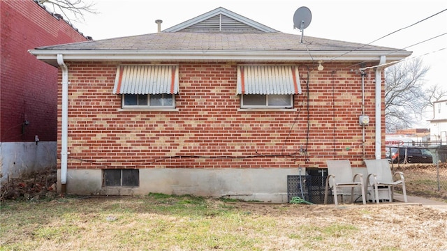 view of property exterior featuring a yard, brick siding, and fence