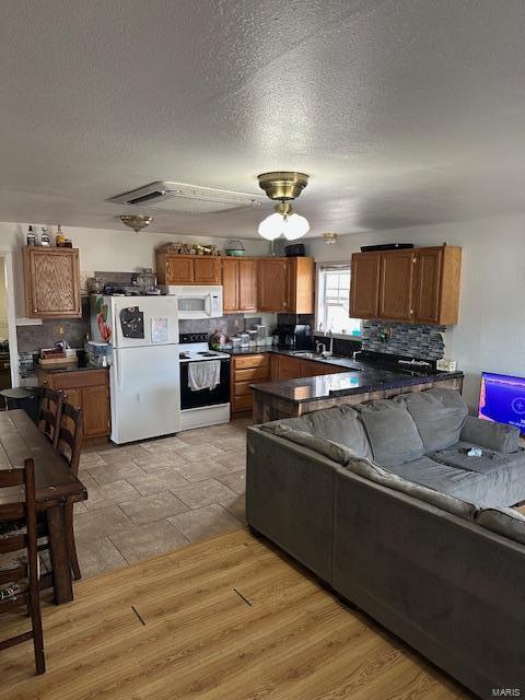 kitchen featuring white appliances, dark countertops, decorative backsplash, and brown cabinets