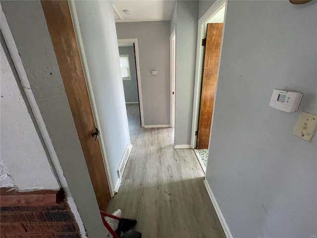 corridor with visible vents, baseboards, and wood finished floors