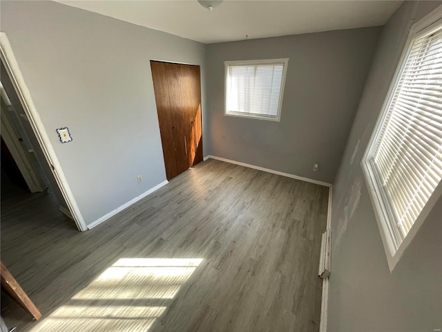 unfurnished bedroom with a closet, wood finished floors, and baseboards