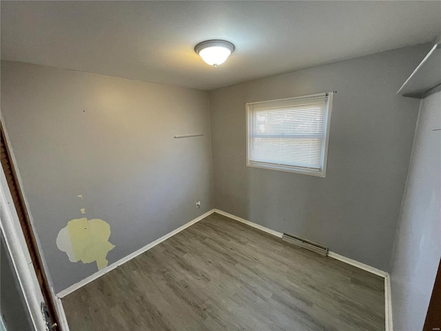 spare room featuring visible vents, baseboards, and wood finished floors