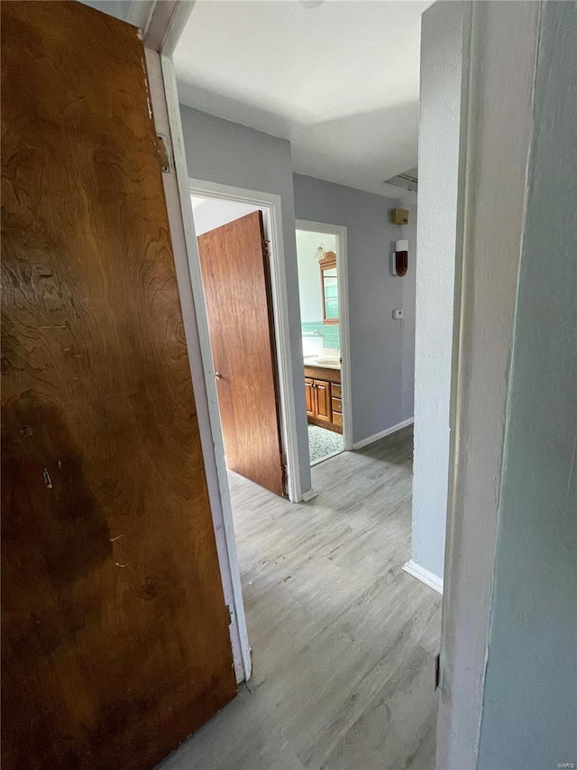 corridor with light wood finished floors and baseboards