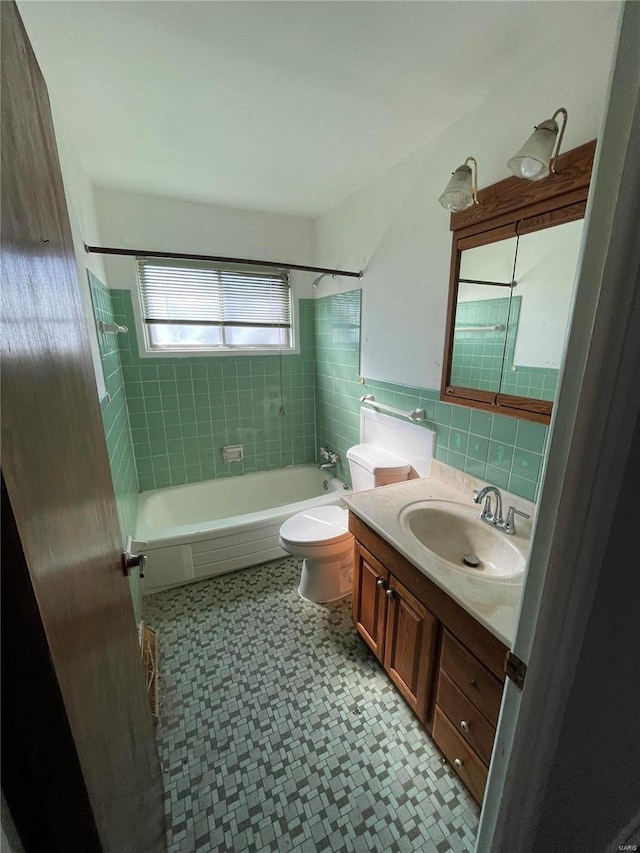 full bath featuring a wainscoted wall, tile walls, bathtub / shower combination, toilet, and vanity