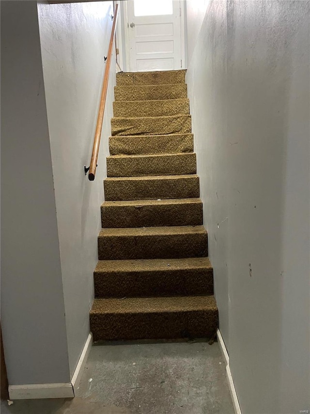 stairs featuring unfinished concrete floors and baseboards