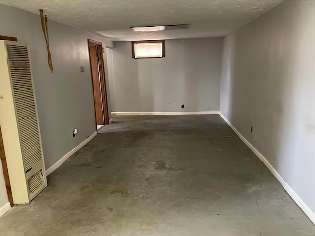 below grade area featuring baseboards, a heating unit, and a textured ceiling