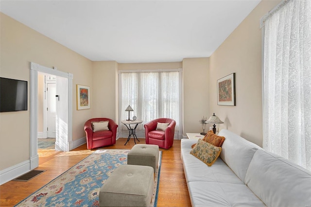 living area featuring wood finished floors, visible vents, and baseboards