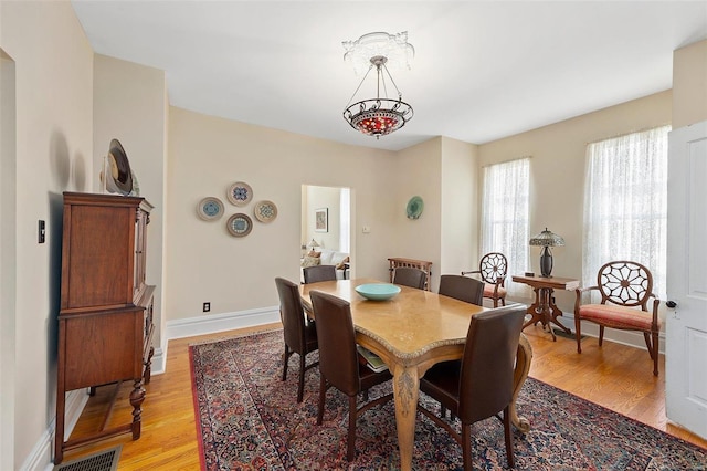 dining space featuring light wood-style floors, baseboards, and visible vents