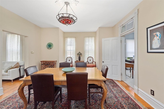 dining space with light wood-type flooring and baseboards