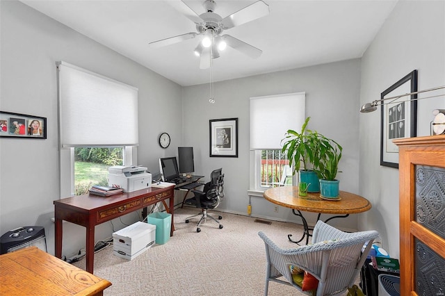 carpeted office space with baseboards, visible vents, and a ceiling fan