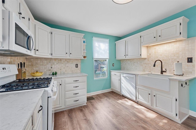 kitchen with white cabinets, white appliances, baseboards, and light wood finished floors