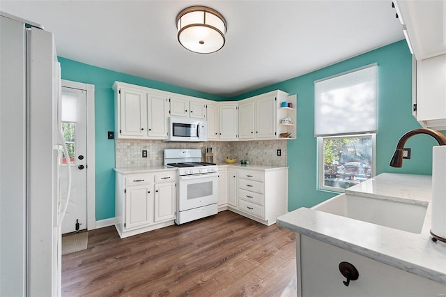 kitchen featuring white appliances, a sink, dark wood finished floors, and decorative backsplash