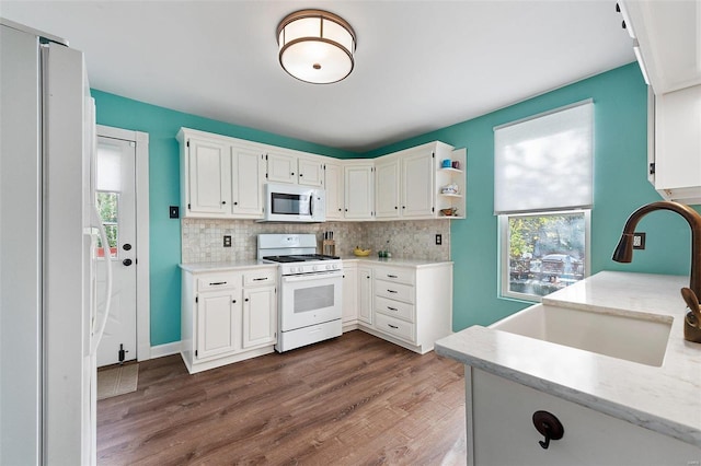 kitchen featuring white appliances, dark wood finished floors, backsplash, and a sink