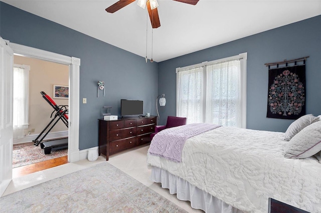 carpeted bedroom with multiple windows, ceiling fan, and baseboards