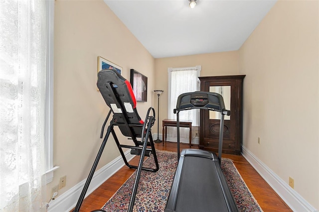 workout room with baseboards and dark wood finished floors