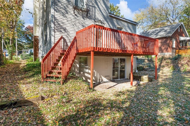 rear view of house featuring stucco siding, a deck, and stairs