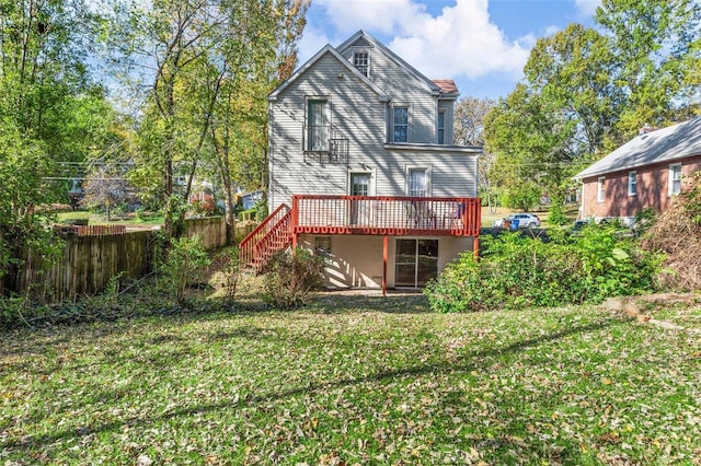 rear view of house with fence, a lawn, a deck, and stairs