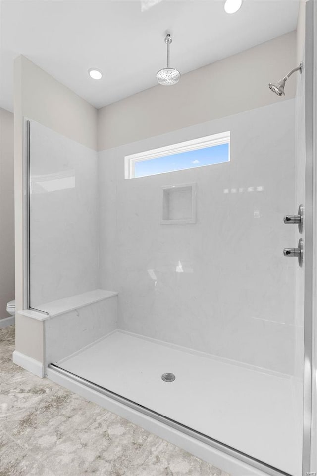 bathroom with toilet, a stall shower, and plenty of natural light