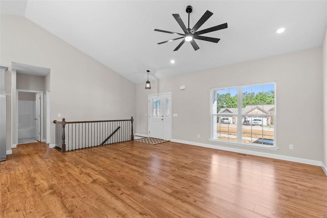 spare room with baseboards, high vaulted ceiling, ceiling fan, and light wood-style floors