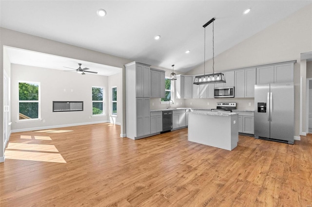 kitchen with a center island, stainless steel appliances, gray cabinets, light wood-style floors, and open floor plan