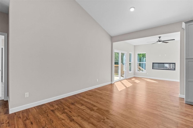 unfurnished living room with ceiling fan, light wood finished floors, a glass covered fireplace, and baseboards