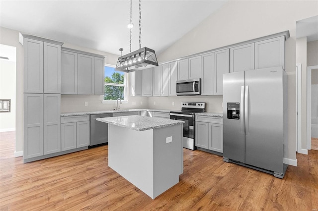 kitchen featuring appliances with stainless steel finishes, a center island, gray cabinets, and a sink