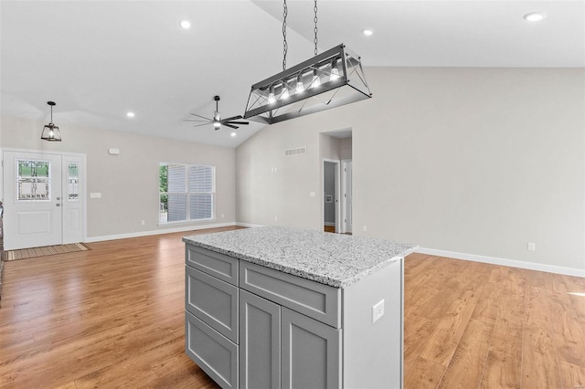 kitchen featuring pendant lighting, gray cabinets, a kitchen island, vaulted ceiling, and light wood-type flooring