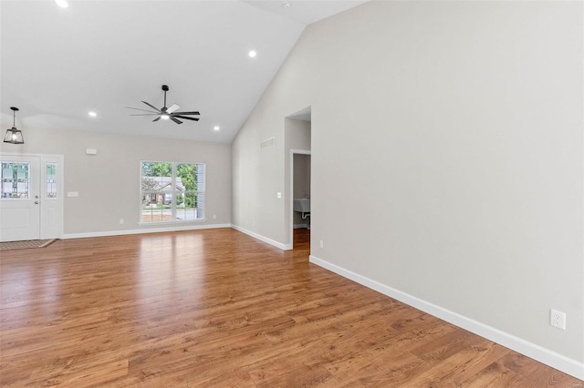 unfurnished living room featuring ceiling fan, high vaulted ceiling, light wood-style flooring, recessed lighting, and baseboards