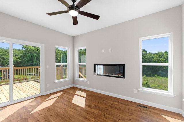 unfurnished living room featuring visible vents, plenty of natural light, baseboards, and wood finished floors