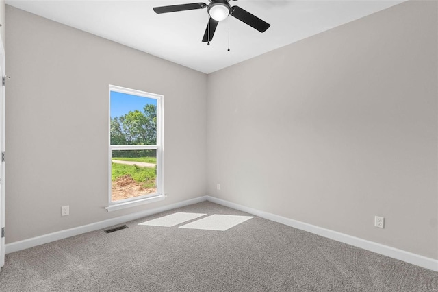 spare room with carpet floors, a ceiling fan, visible vents, and baseboards