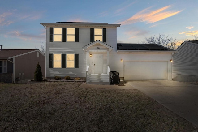 view of front of property with an attached garage, driveway, a lawn, and solar panels