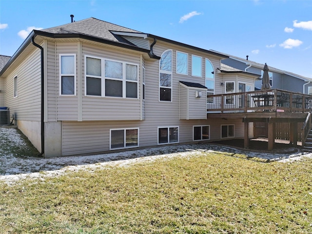 rear view of house featuring a deck, central AC unit, a lawn, and roof with shingles