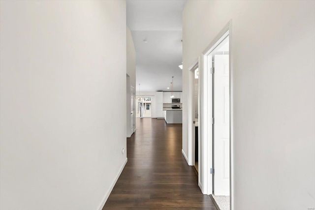 hall featuring dark wood-style flooring and baseboards