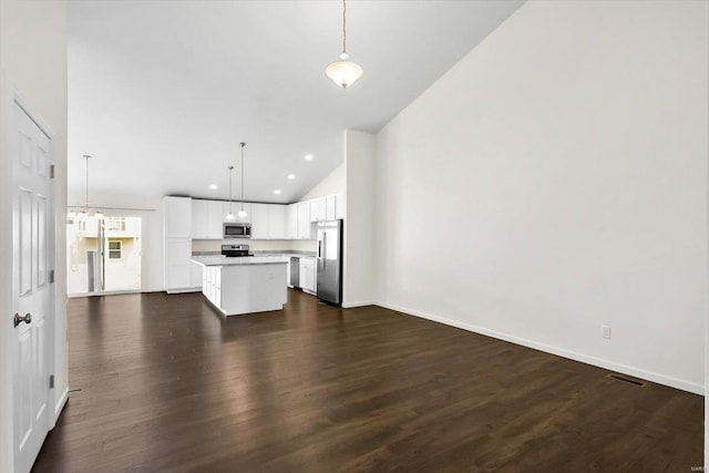 kitchen featuring stainless steel appliances, a kitchen island, visible vents, open floor plan, and dark wood-style floors