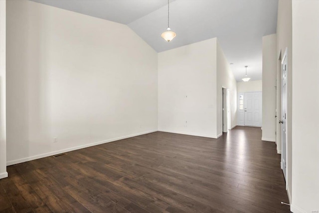 spare room with vaulted ceiling, dark wood finished floors, and baseboards