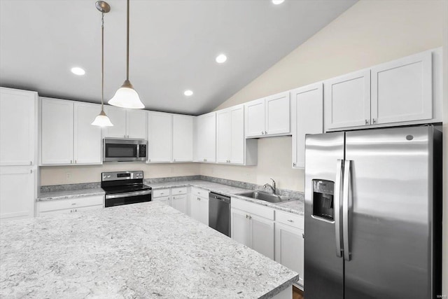 kitchen featuring appliances with stainless steel finishes, hanging light fixtures, vaulted ceiling, white cabinetry, and a sink