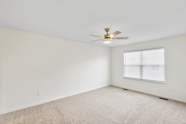 spare room with a ceiling fan, visible vents, light carpet, and baseboards