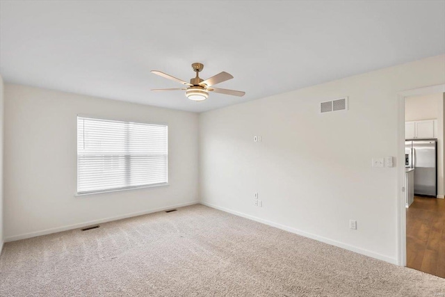 unfurnished room featuring carpet floors, ceiling fan, visible vents, and baseboards